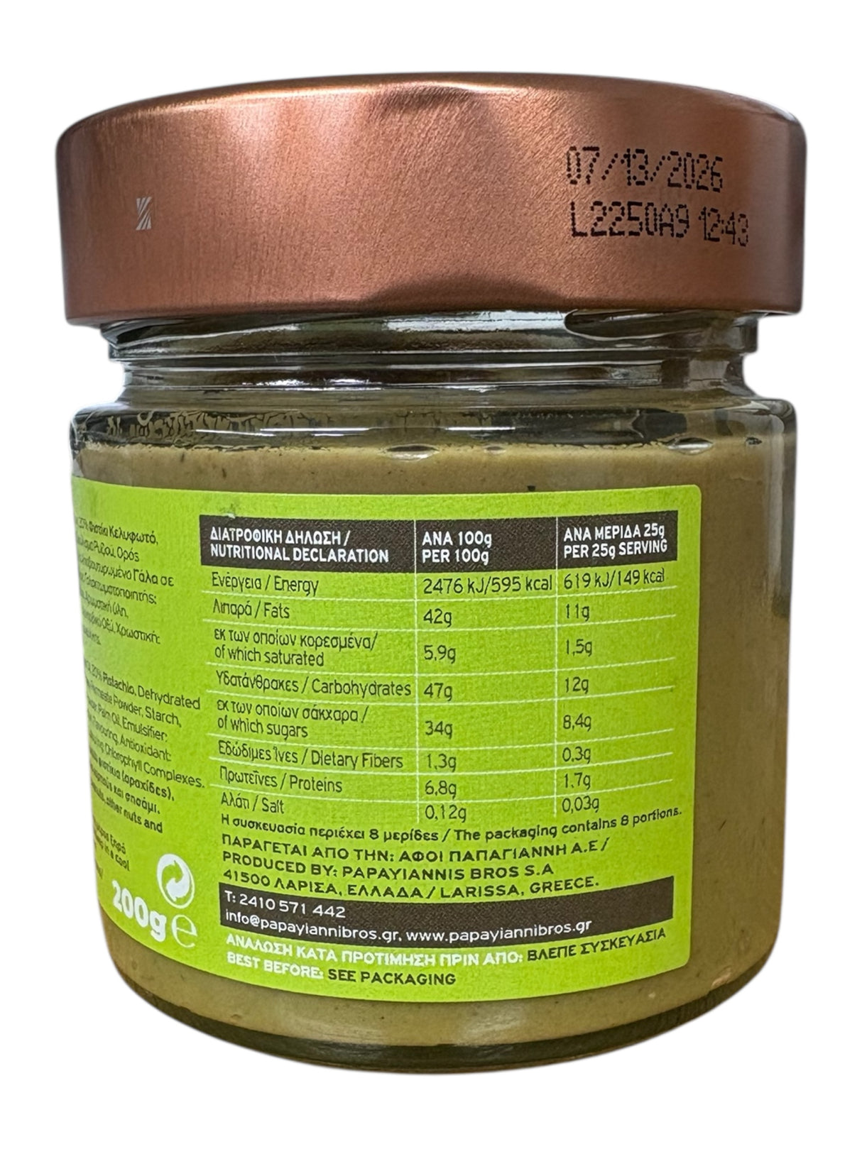 Jar of green spread with a copper lid and nutritional label on a white background
