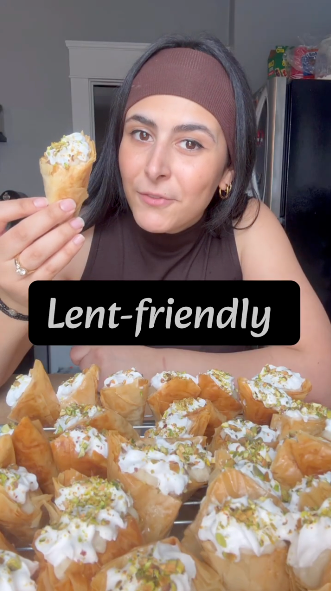 Woman holding a Lent-friendly Trigona Panoramatos Greek dessert made with crispy phyllo triangles topped with cream and pistachios.