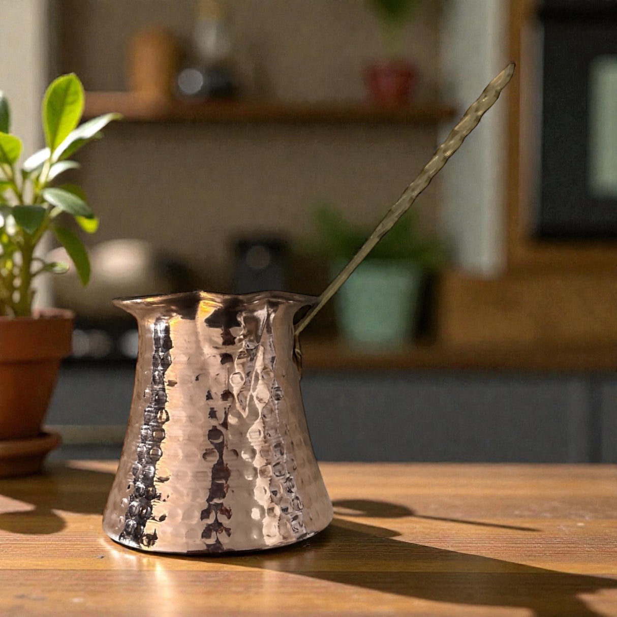 Copper Greek coffee pot with a spoon on a wooden table, blurred indoor background