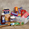 Assorted food items including cookies, honey, and chocolate bars on a wooden surface with a gray background.