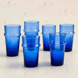 Six cobalt blue glass tumblers with a stacked rim design, arranged on a light beige background with a faint repeating watermark.