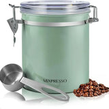 A mint green metal coffee bean canister with a clear lid and stainless steel clasp, shown with a metal measuring scoop and a small pile of coffee beans on a white background. The brand name 'Mixpresso' is printed on the front.